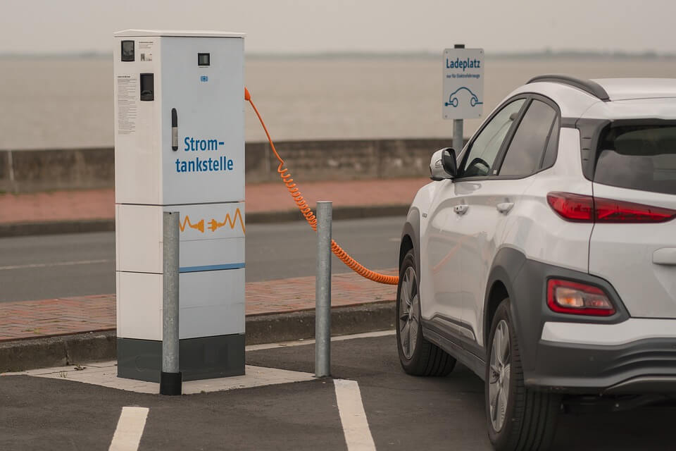 Elektroauto lädt an einer Stromtankstelle am Meer auf. Umweltfreundliche Mobilität in moderner Landschaft.