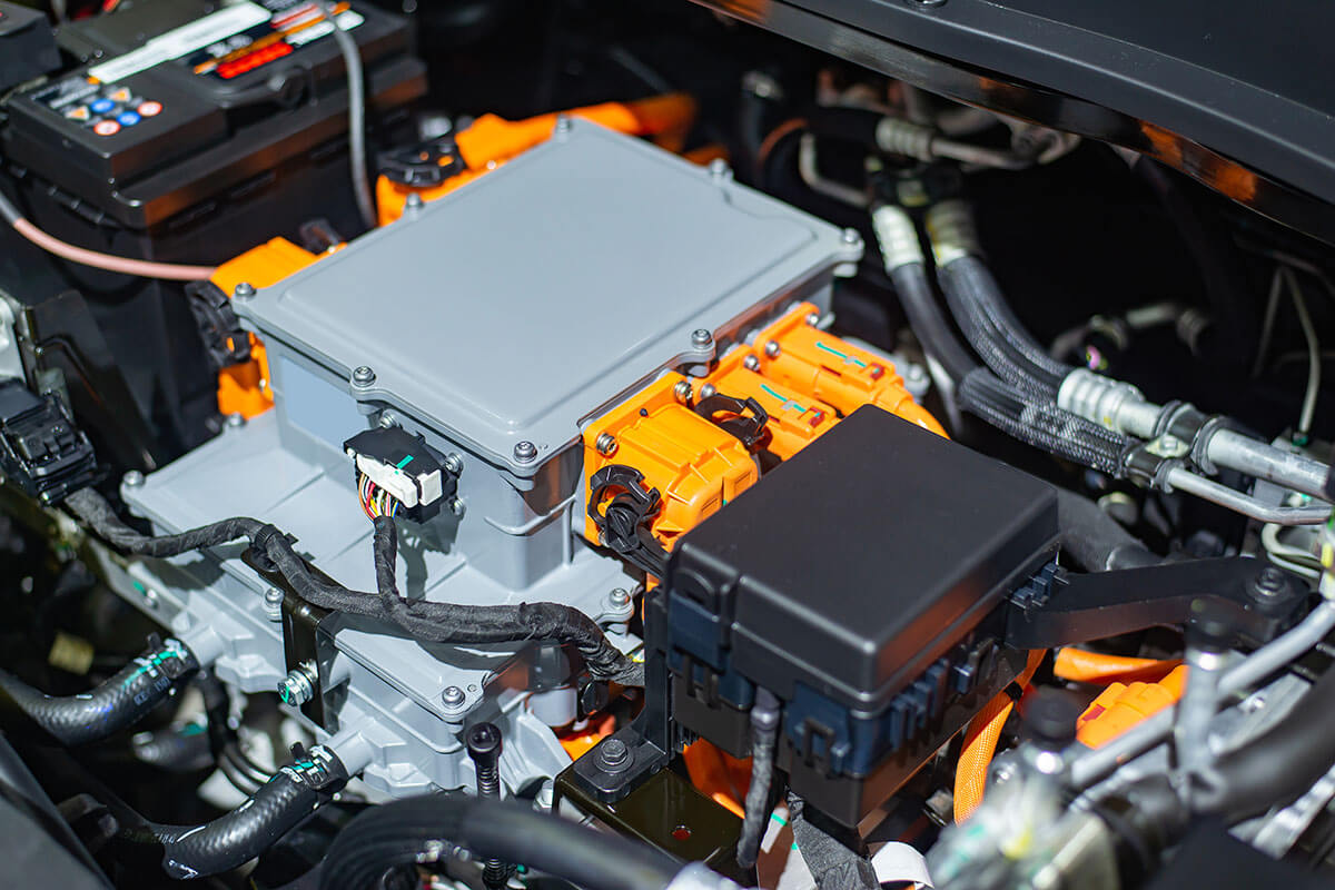 Elektrischer Fahrzeugmotor mit orangefarbenen Kabeln und Anschlüssen für nachhaltige Antriebstechnologie.
