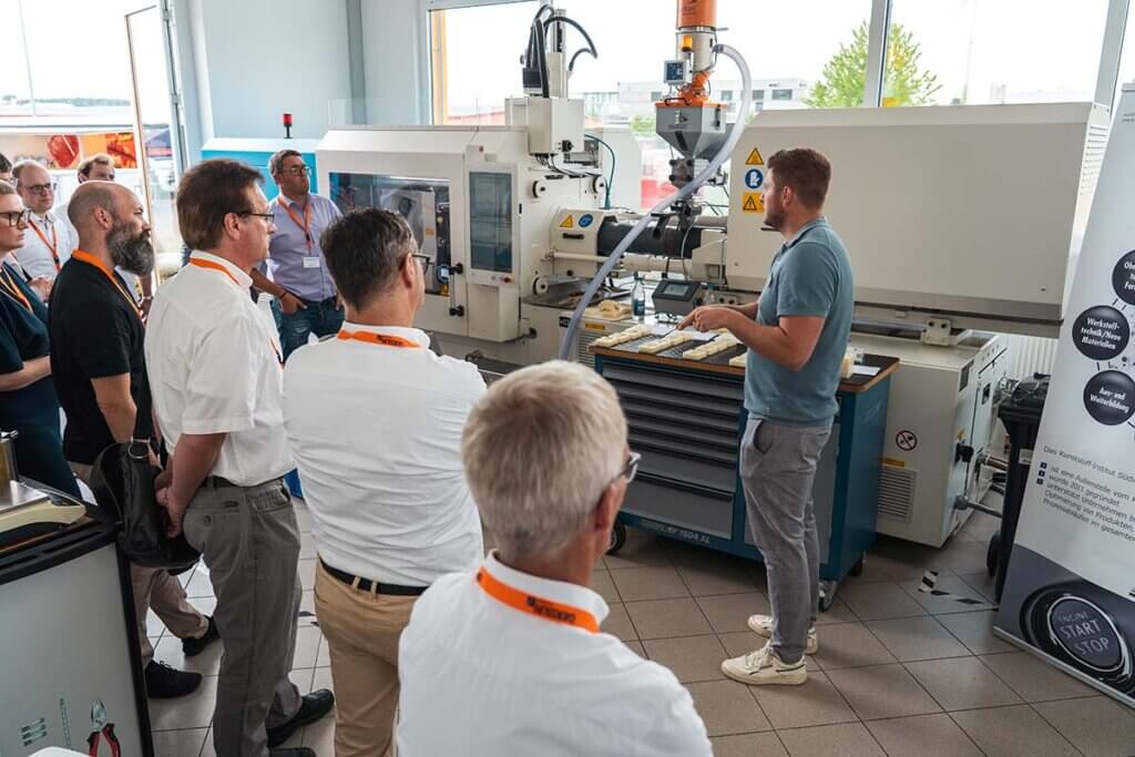 Menschen lernen an einer Kunststoffmaschine in einem industriellen Workshop.